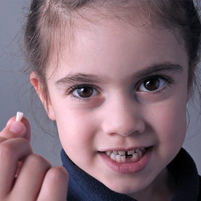 Little girl holding up her tooth
