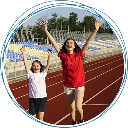 Two young girls on a track with their hands in the air