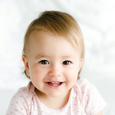 A baby smiling with two top and two bottom teeth showing