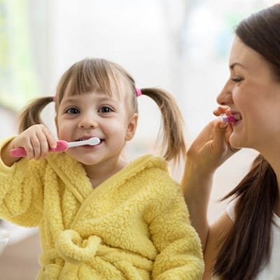 A mother and daughter brushing their teeth at home