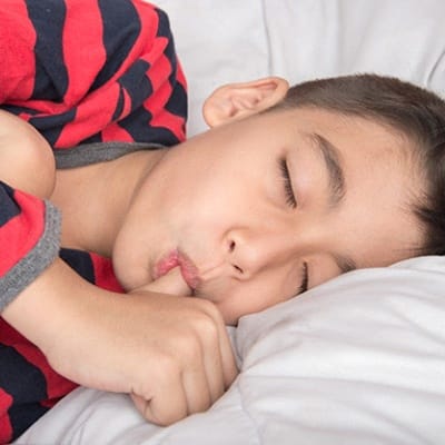 A boy asleep and sucking his thumb