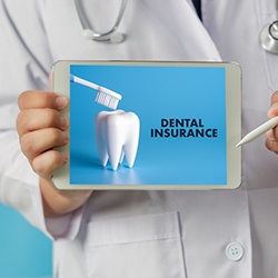 Dentist in white coat holding digital tablet with Dental Insurance on it