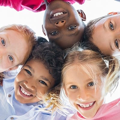 Circle group of kids smiling while looking down at camera