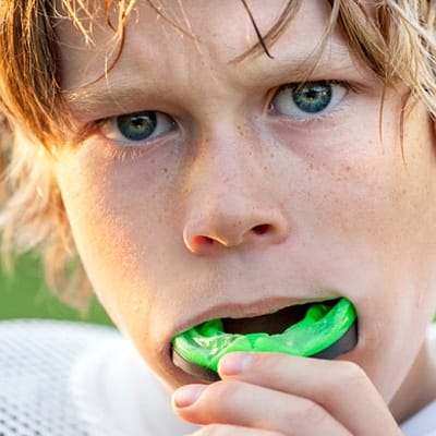 A young boy wearing a sportsguard for a football game