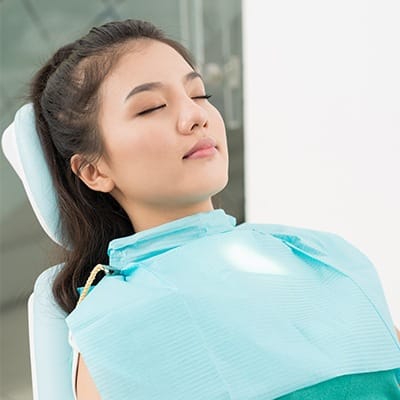 Relaxed young woman with eyes closed in dental chair