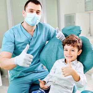 A young boy and his dentist giving a thumbs up while in the dentist’s chair