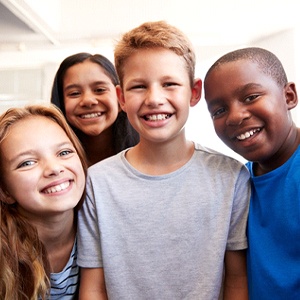 A group of boys and girls smiling after receiving beneficial fluoride treatment to combat tooth decay