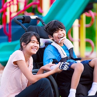 Laughing young woman and teen boy in wheelchair