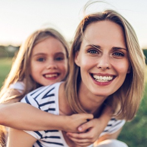 A mother giving her daughter a piggyback ride 