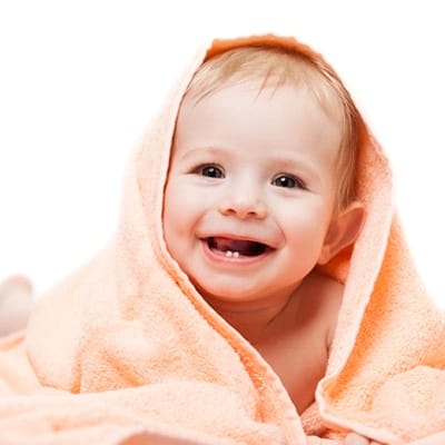 A baby smiling with a towel wrapped around it