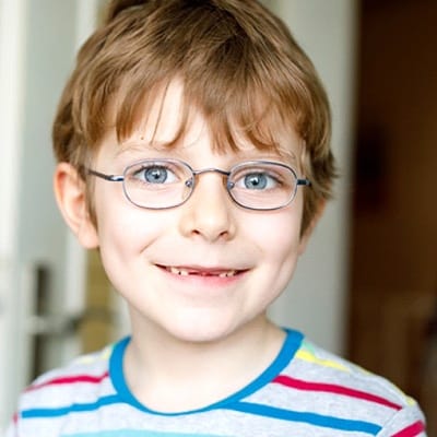 A young boy smiling with a few missing teeth