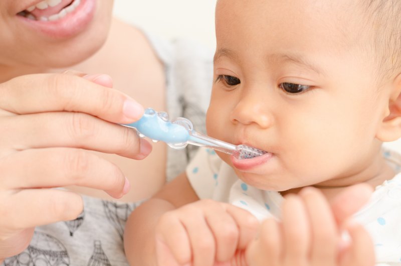 a parent brushing their baby’s teeth