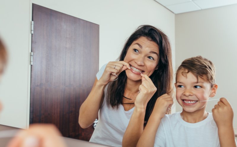 a young boy and his mother flossing their teeth