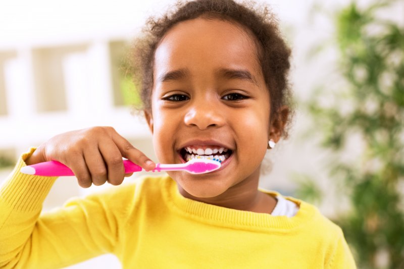 a little girl brushing her teeth after seeing a McKinney pediatric dentist