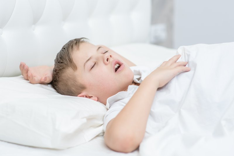 a young boy lying on his back asleep with his mouth open