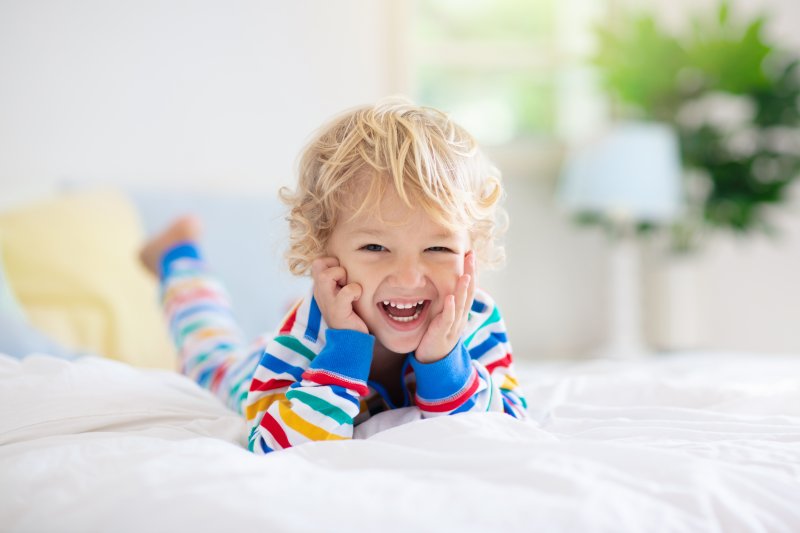 a young child lying on their stomach on a bed and smiling