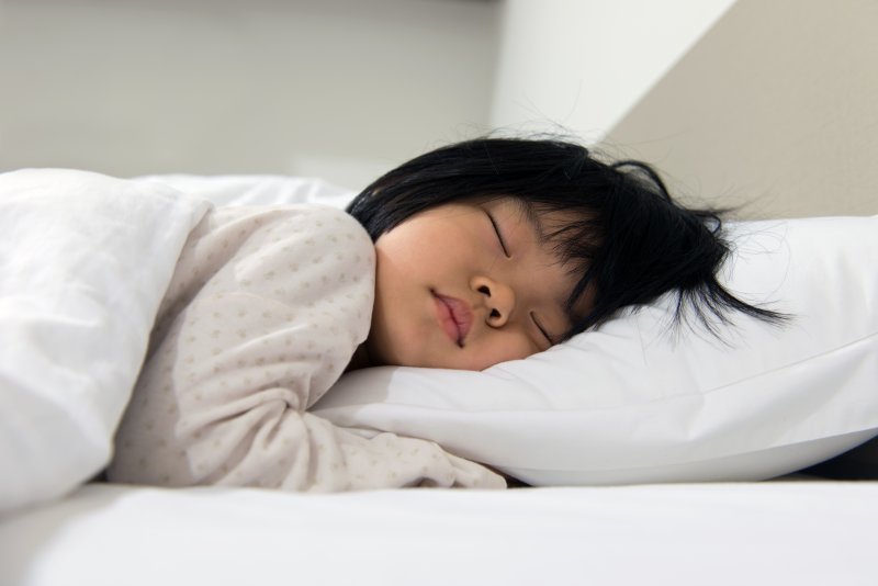 a young child asleep lying on their stomach with their head on a pillow 