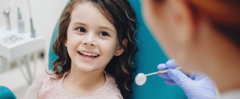 a little girl smiling at her dentist during a regular checkup