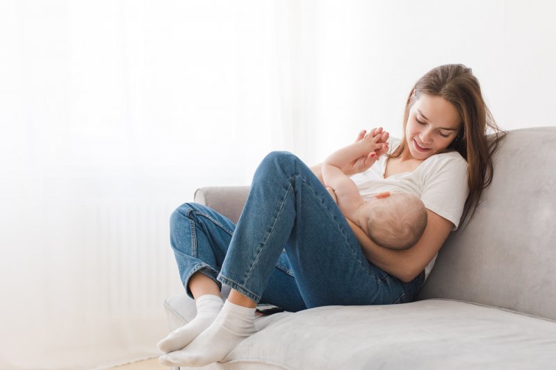 a mother nursing her baby while seated on a couch