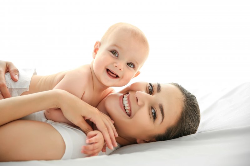 a mother and her baby lying on a bed laughing and playing together