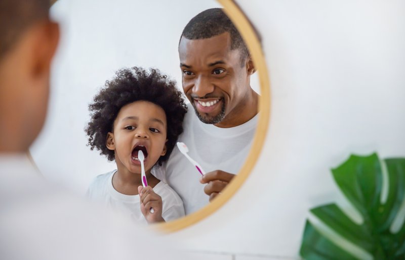 a father and his child brushing their teeth before bedtime