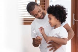 father and son brushing teeth together 