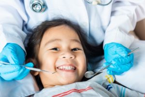 a child smiling as they get their mouth cleaned by a pediatric dentist