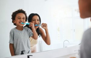 a mother and child brushing their teeth together
