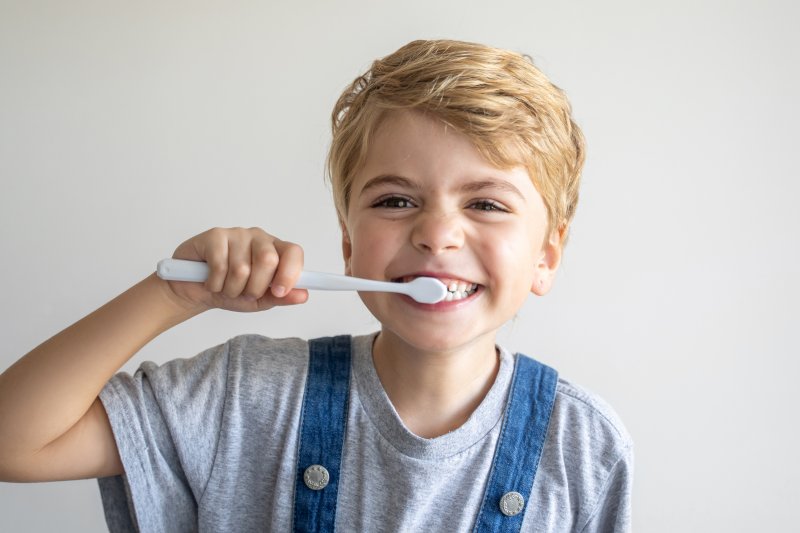 young boy brushing with fluoride toothpaste