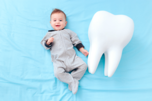 a young infant next to a giant tooth