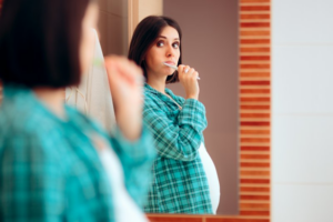 Pregnant woman brushing her teeth in the mirror